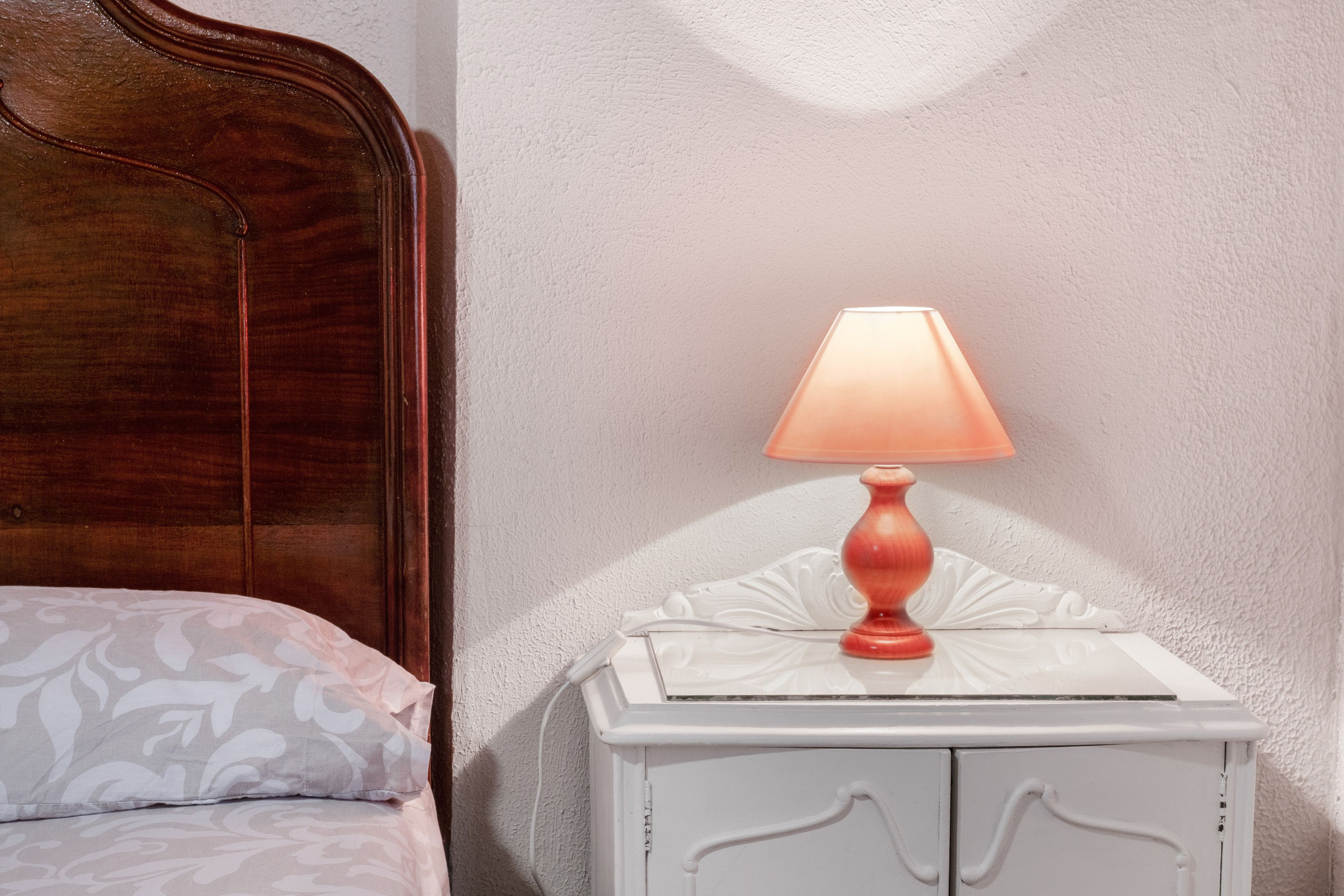 En seng med et mønstret pude og et natbord med en lampe.