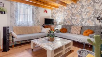 Una sala de estar con un sofá, una mesa de centro, un televisor y un cactus.