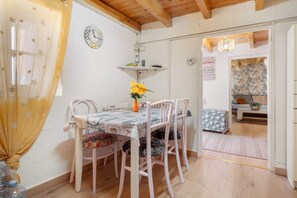 Een eethoek met een tafel voor vier personen, een klok aan de muur en een deur naar een andere kamer.