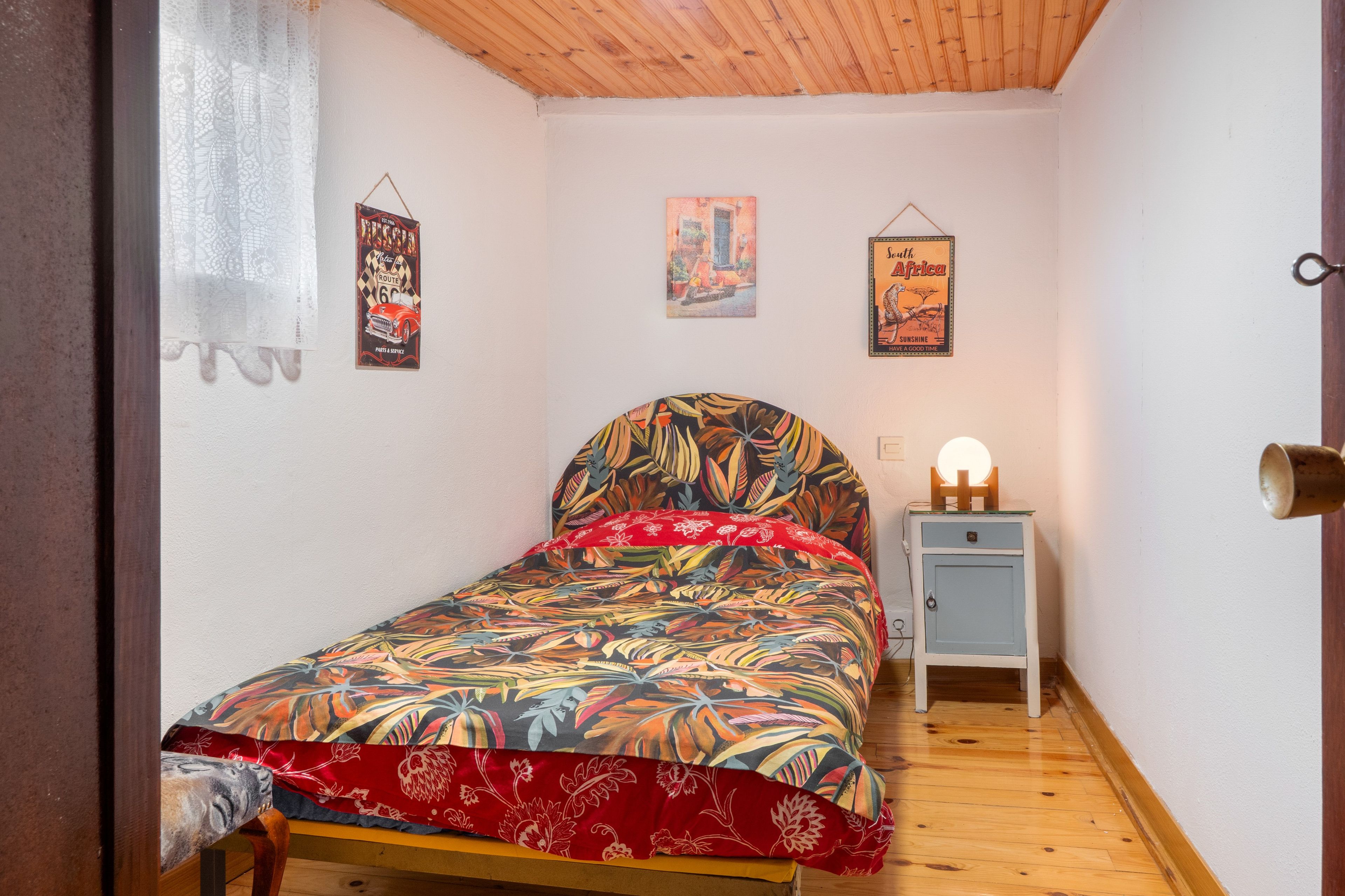 Un dormitorio con cama, mesita de noche, lámpara y adornos en la pared.