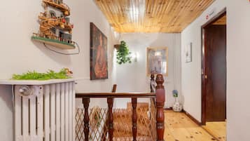 Una escalera de madera que lleva a una puerta, un radiador y una pequeña mesa con plantas.