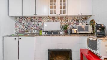 Una cocina compacta con armarios blancos, un salpicadero estampado y una encimera roja.