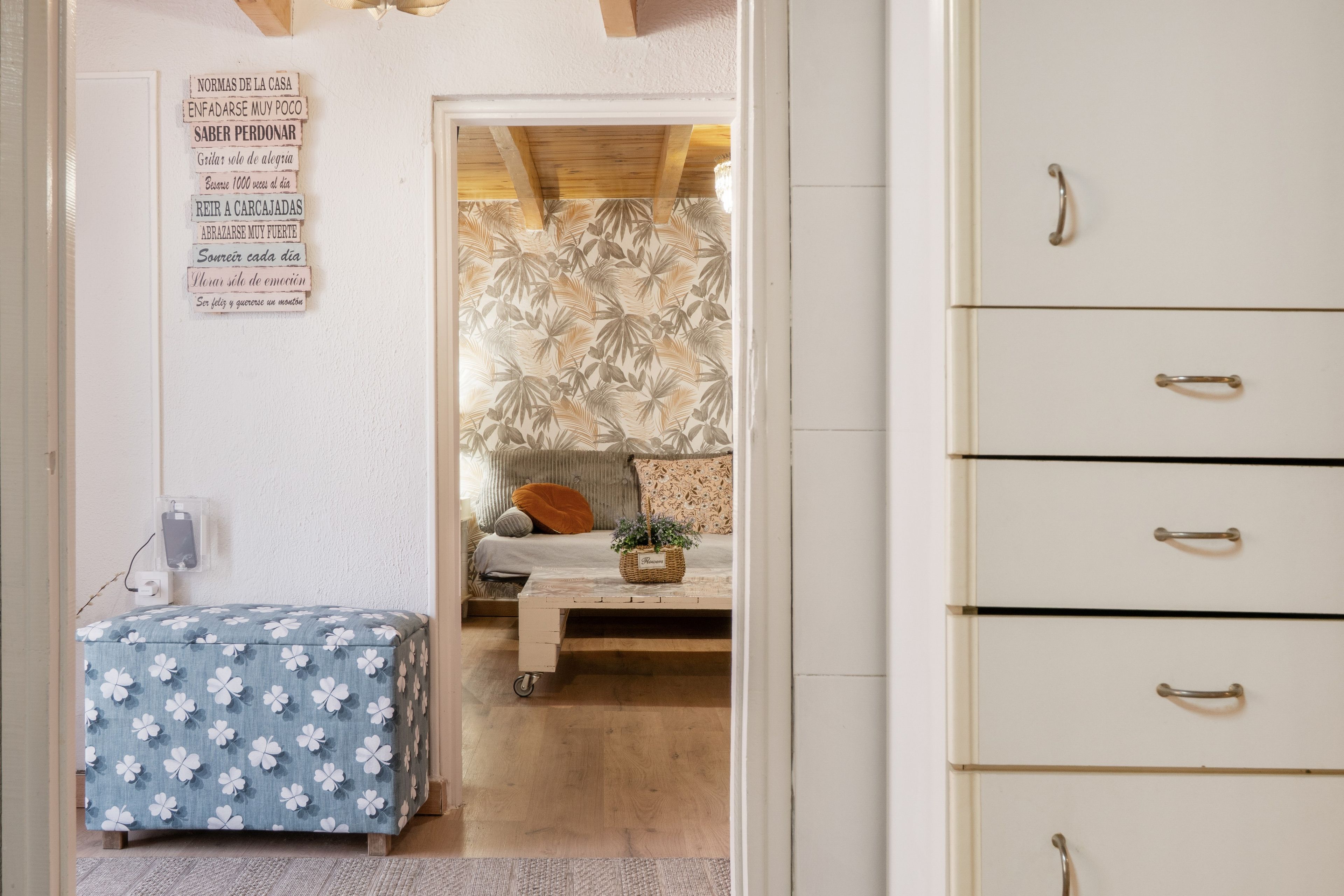 Een slaapkamer met een bed, nachtkastje, kledingkast en een muur met een lijst zinnen.