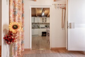 A doorway leading to a kitchen with wooden cabinets, a tiled backsplash, and a hanging wooden rack.