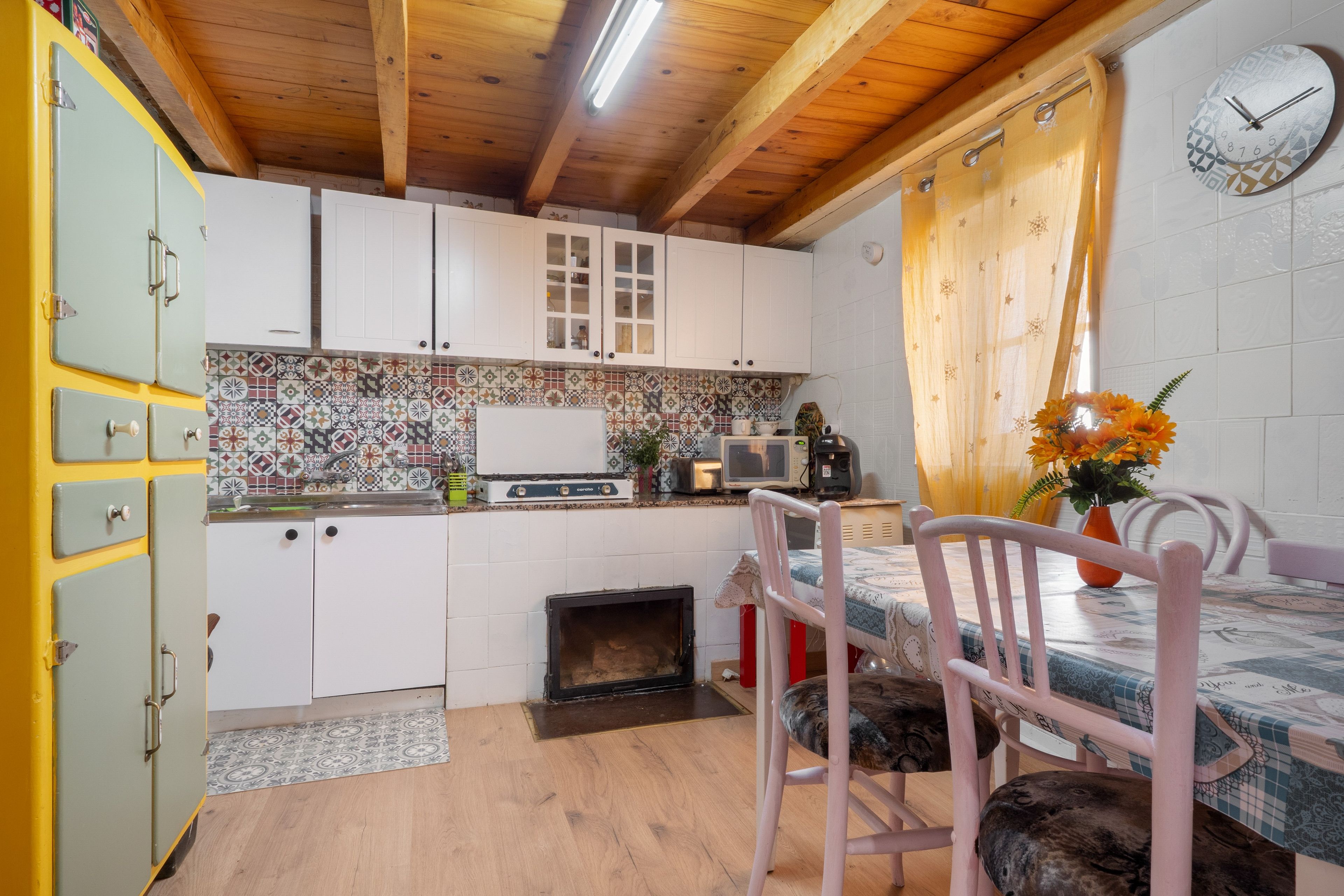 A kitchen with white cabinets, a tiled backsplash, a stove, a microwave, and a dining area with a table and chairs.