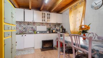 A kitchen with white cabinets, a tiled backsplash, a stove, a microwave, and a dining area with a table and chairs.