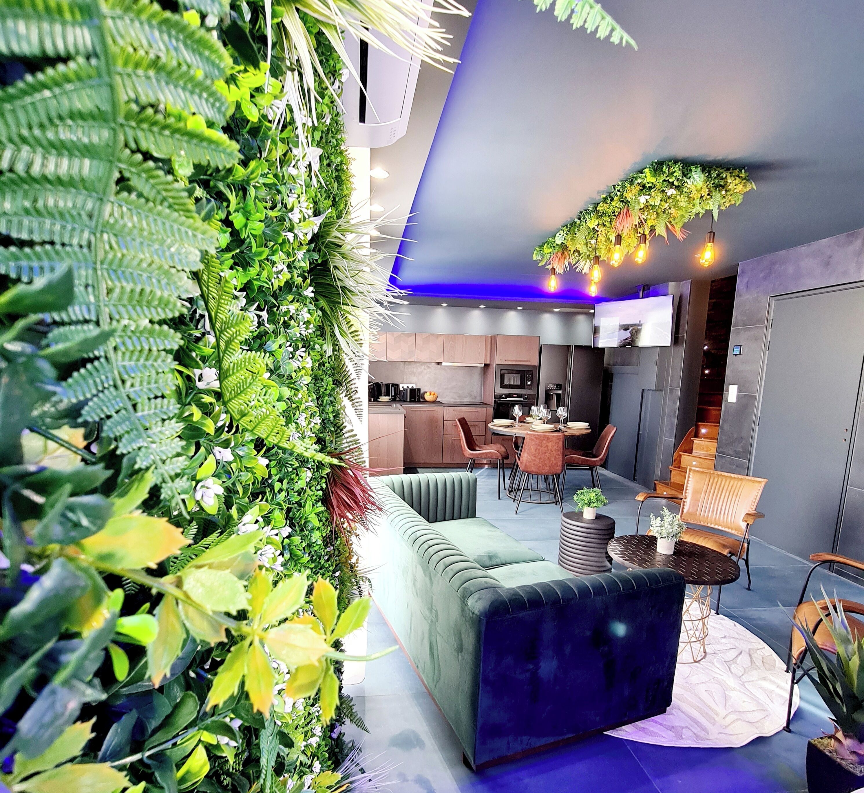 A modern interior with a green wall, a sofa, a dining area, and a kitchen.