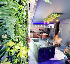 Ein modernes Interieur mit einer grünen Wand, einer Couch, einem Essbereich und einer Küche.