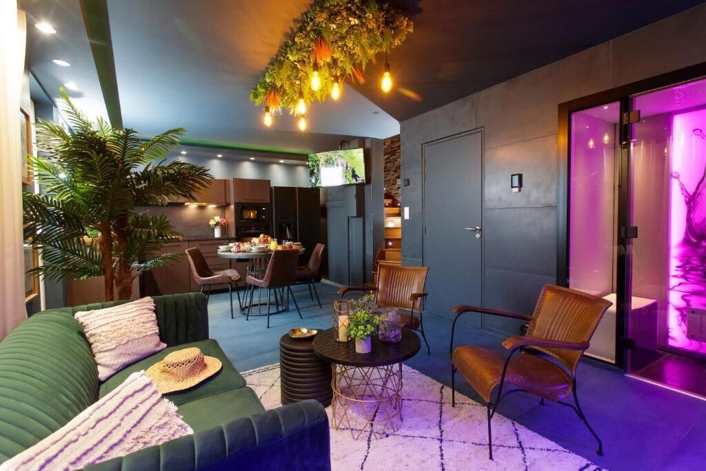 Een modern interieur met een groene bank, een eethoek en een paars verlichte ruimte.