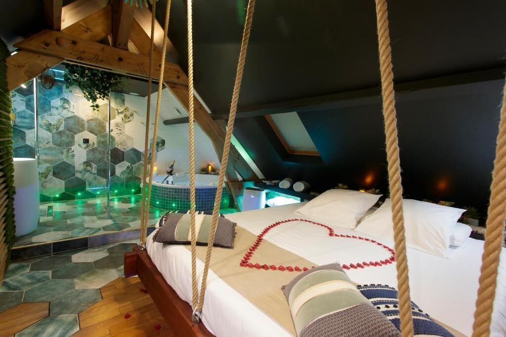 A bedroom with a hanging bed, a hexagonal tile wall, and a view of the night sky.