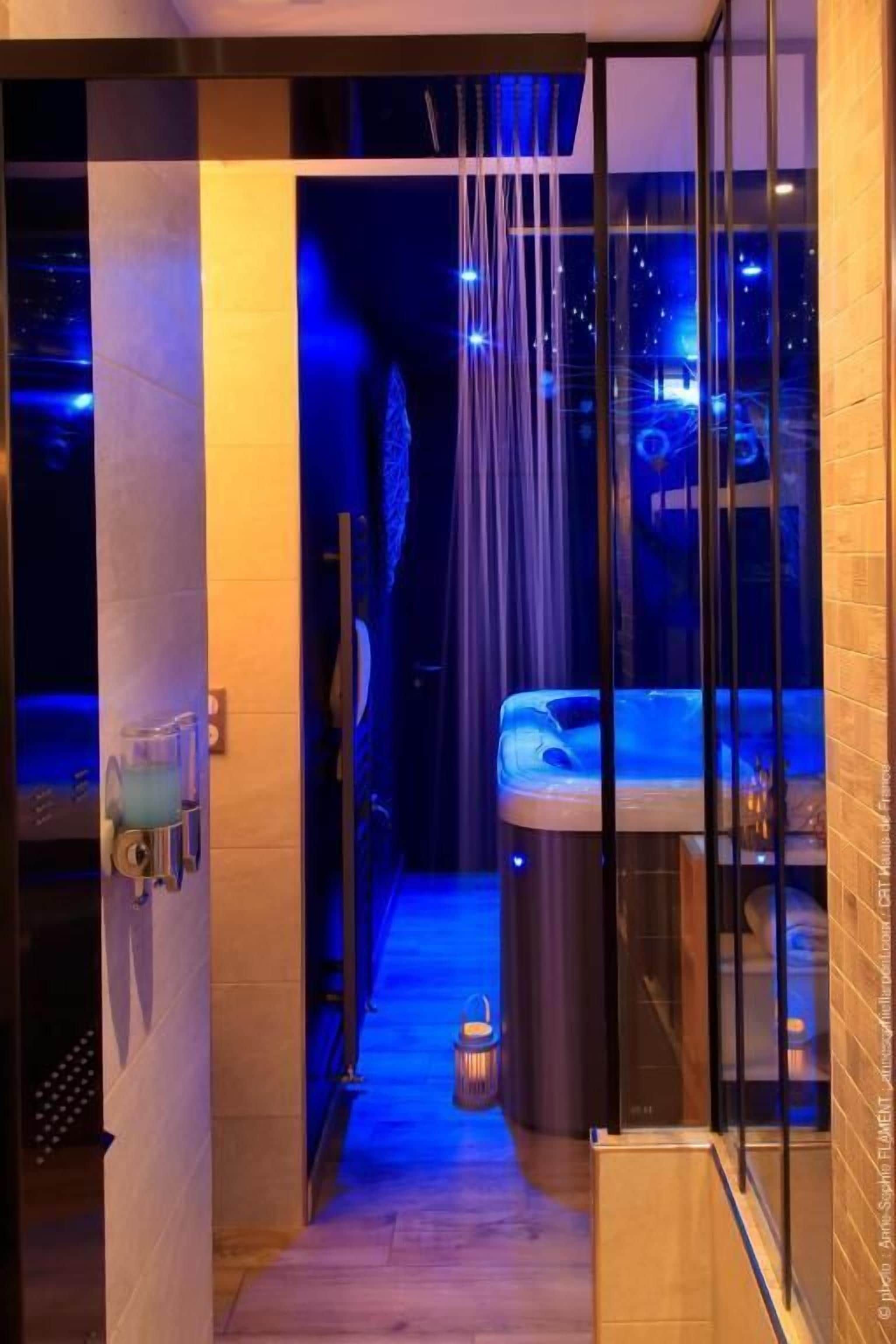 Ein spa-ähnlicher Bereich mit Glaswänden, einer Whirlwanne, einem kleinen Mülleimer und Holzboden.