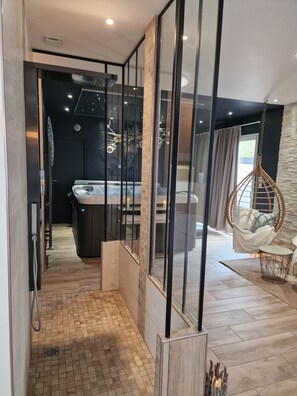 A modern interior with a glass partition, a hanging chair, and a view of a room with a bathtub. - Sweety Loft - Accommodation with Spa (Friville-Escarbotin)