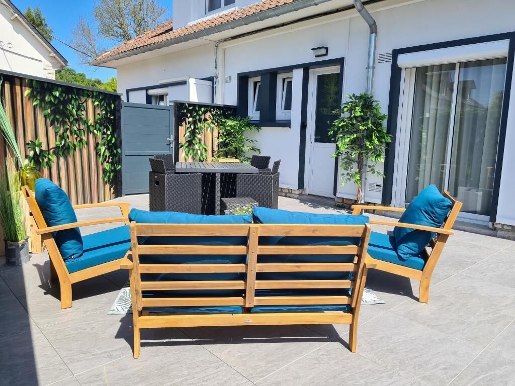 Ein Sitzbereich im Freien mit einer hölzernen Bank, Stühlen, einem Tisch und Topfpflanzen.