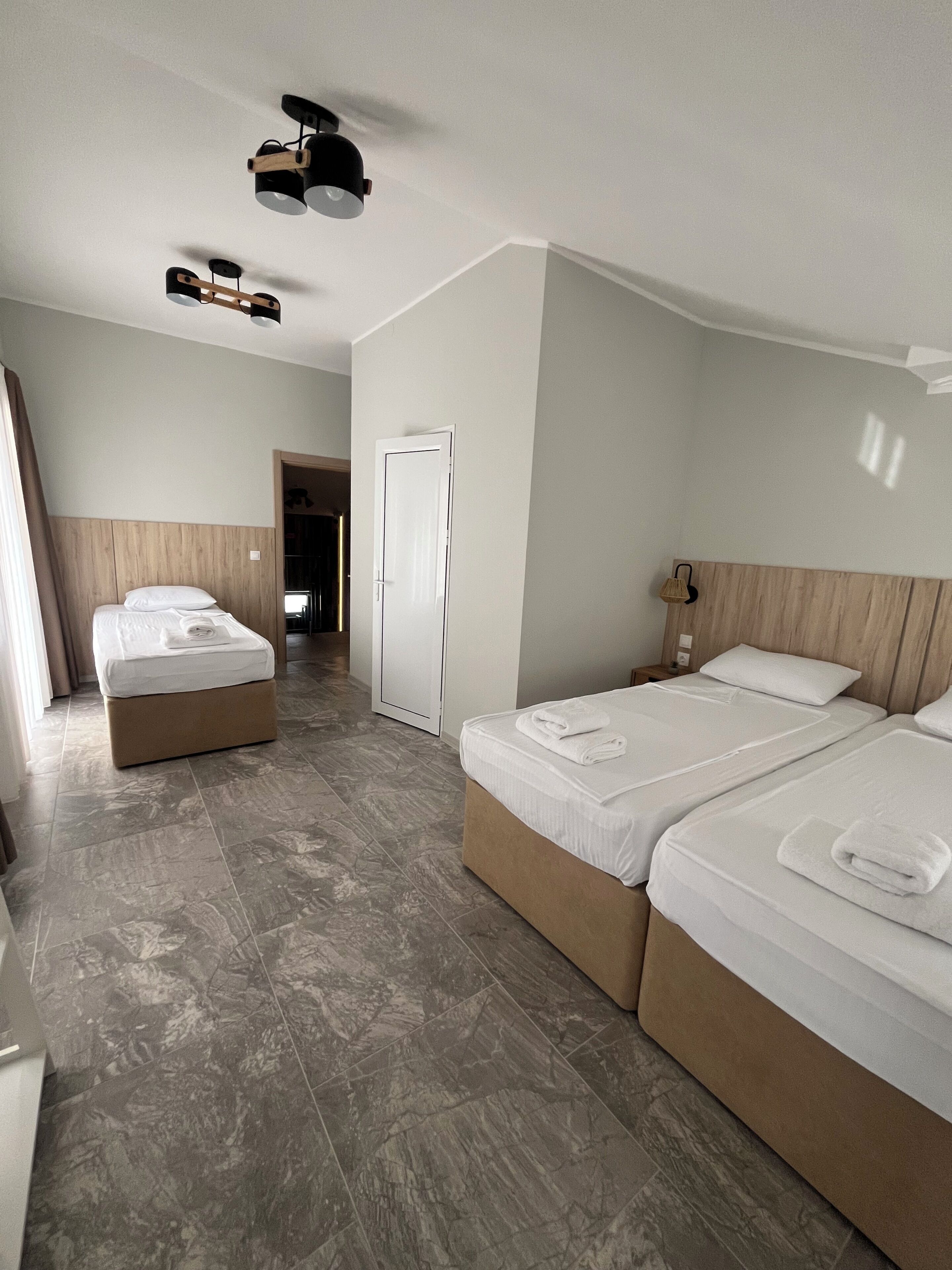 Una camera d'albergo con un letto, un comodino, un armadio e una lampada a sospensione.