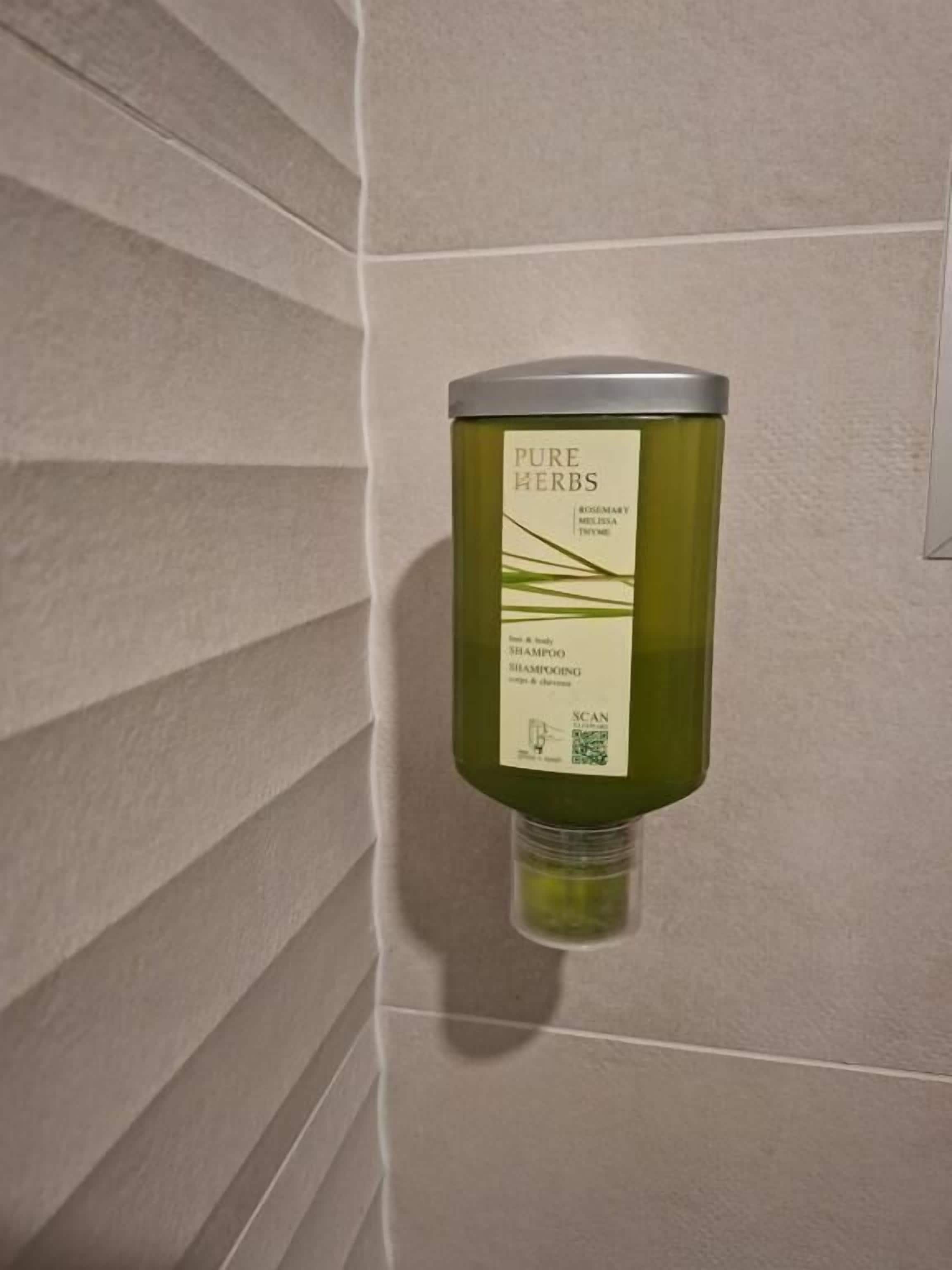 A wall-mounted dispenser of Pure Herbs shampoo and conditioner.