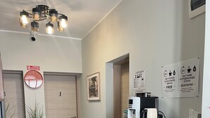 Un vestíbulo de hotel con una máquina de café, un reloj y un cartel que indica servicio de café y agua las 24 horas del día.