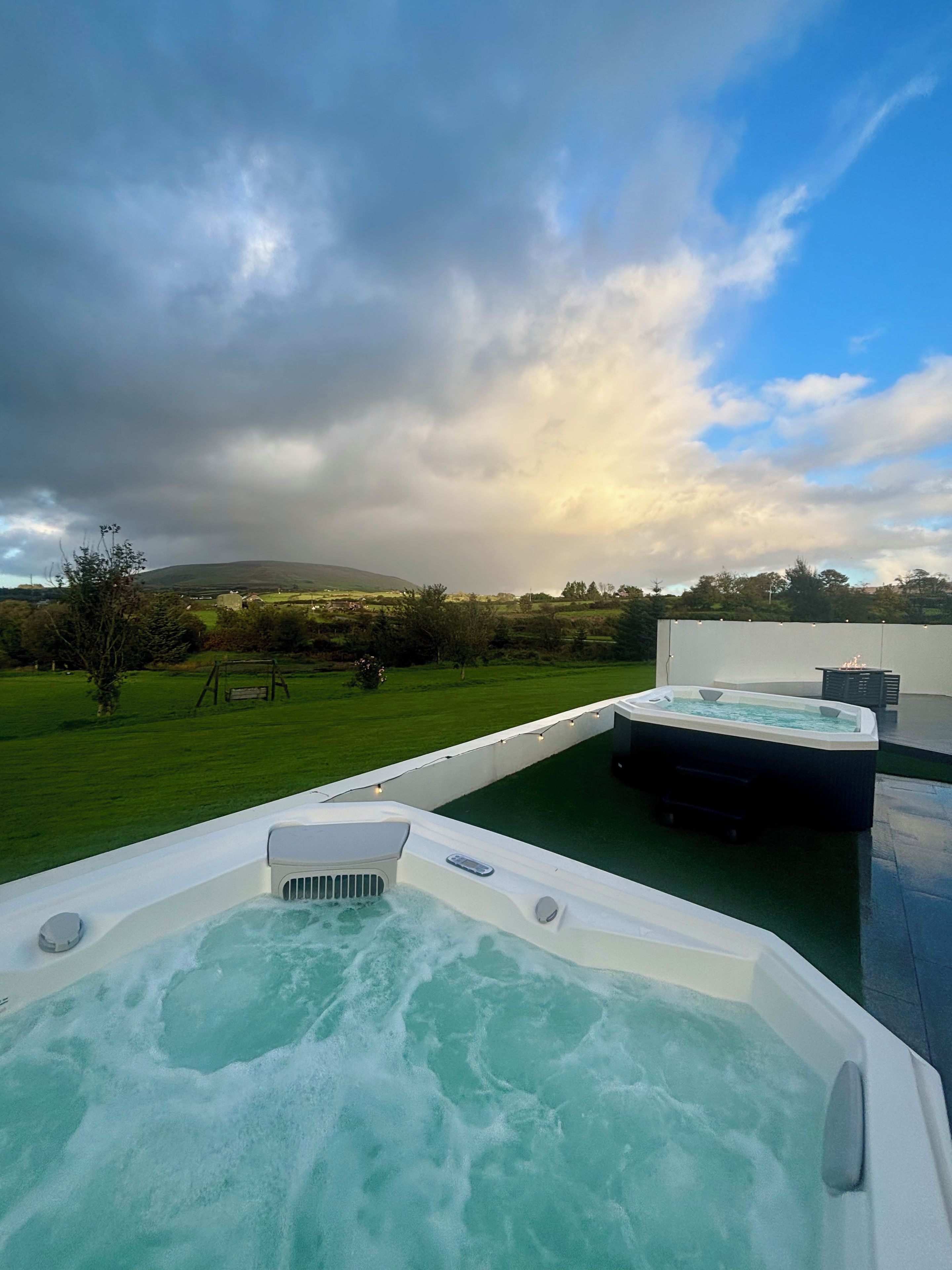A hot tub area with a view of a grassy landscape and a hill in the background.