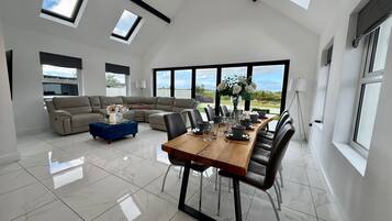 A spacious living area with a large dining table, a sofa, and a view of the outdoors.