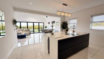 A modern kitchen with a central island, large windows, and a dining area with a view.