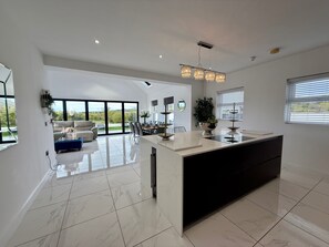 Une cuisine moderne dotée d’un grand îlot central, un coin repas offrant une vue agréable et un salon avec un canapé et une table basse.