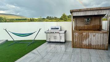 A patio with a barbecue grill, a wooden bar area, and a hammock.