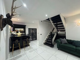 Un interior moderno con una zona de bar, una escalera y un sofá verde.