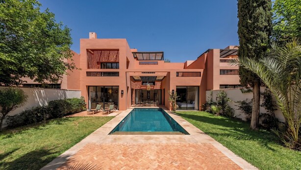 A modern two-story building with a swimming pool in the center, surrounded by well-maintained grass and trees. - Riad Jasmin – Al Maaden Golf – Marrakech (Marrakech)