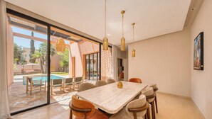 A dining area with a large table, chairs, and hanging pendant lights. - Riad Jasmin – Al Maaden Golf – Marrakech (Marrakech)