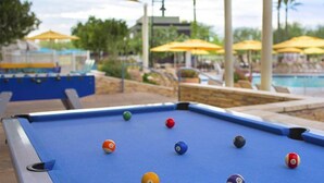 A pool table with billiard balls, a pool table, and a pool area with umbrellas and palm trees. - 1 Bedroom Villa at Marriott Canyon Resort (Phoenix)
