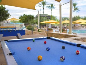A pool table with billiard balls, a pool table, and a pool area with umbrellas and palm trees. - 1 Bedroom Villa at Marriott Canyon Resort (Phoenix)