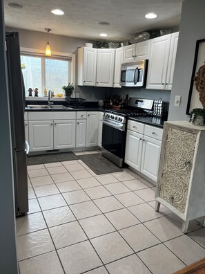 A kitchen with white cabinets, a stainless steel stove, a microwave, and a refrigerator.
