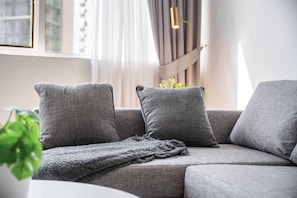 Ein modernes Wohnzimmer mit einem grauen Sofa, einer Decke und einer Stehlampe.