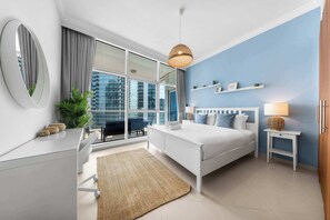 A modern bedroom with a bed, bedside tables, a desk, a large window, and a view of the city. - StayShort - Elegant 4, Bedroom in Dubai Marina that Sleeps 10 (Dubai)