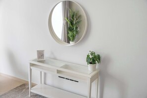 A white console table with a mirror above it, a potted plant on the table, and a framed picture on the table. - StayShort - Elegant 4, Bedroom in Dubai Marina that Sleeps 10 (Dubai)