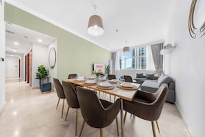A modern dining area with a long table set for six, surrounded by brown chairs with gold legs. - StayShort - Elegant 4, Bedroom in Dubai Marina that Sleeps 10 (Dubai)