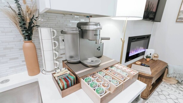A kitchenette with a coffee maker, tea infuser, and a variety of tea and coffee pods. - Modern Condo Near Downtown Fort Worth & Stockyards (Fort Worth)
