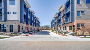 A modern apartment building with a central courtyard, multiple balconies, and a clear sky. - Modern Condo Near Downtown Fort Worth & Stockyards (Fort Worth)