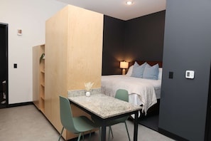 A compact room with a bed, a desk, and a chair.