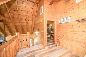 A wooden interior with a staircase, a sign that says 'TRAVEL,' and a wall with the phrase 'DON'T WAKE THE BEAR.' - Mountain View Retreat | Perfect for Groups, Events & Getaways (Sevierville)