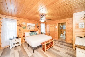 A wooden-paneled room with a bed, a nightstand, a bench, and a ceiling fan. - Mountain View Retreat | Perfect for Groups, Events & Getaways (Sevierville)