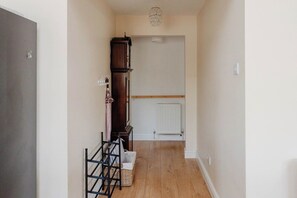 Ein Korridor mit Holzboden, einem Heizkörper, einem hohen Holzschrank und einer Kristallleuchtre.