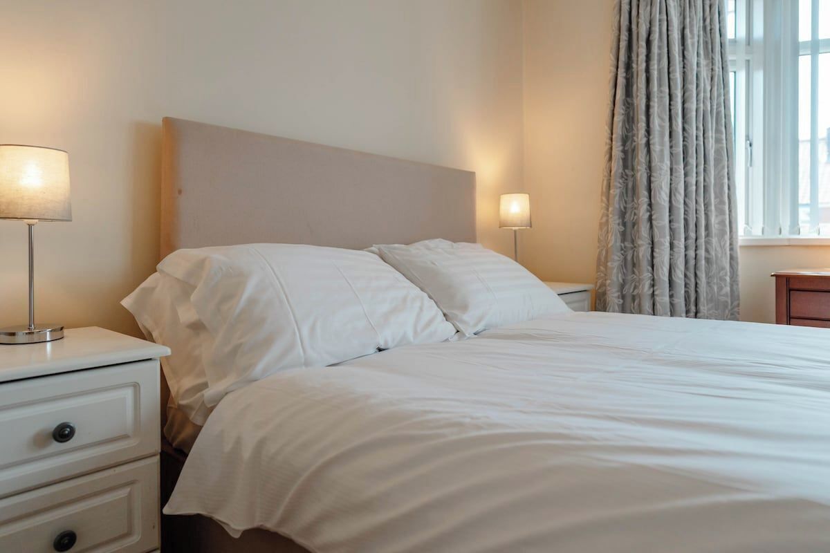 A neatly made bed with white linens in a hotel room.
