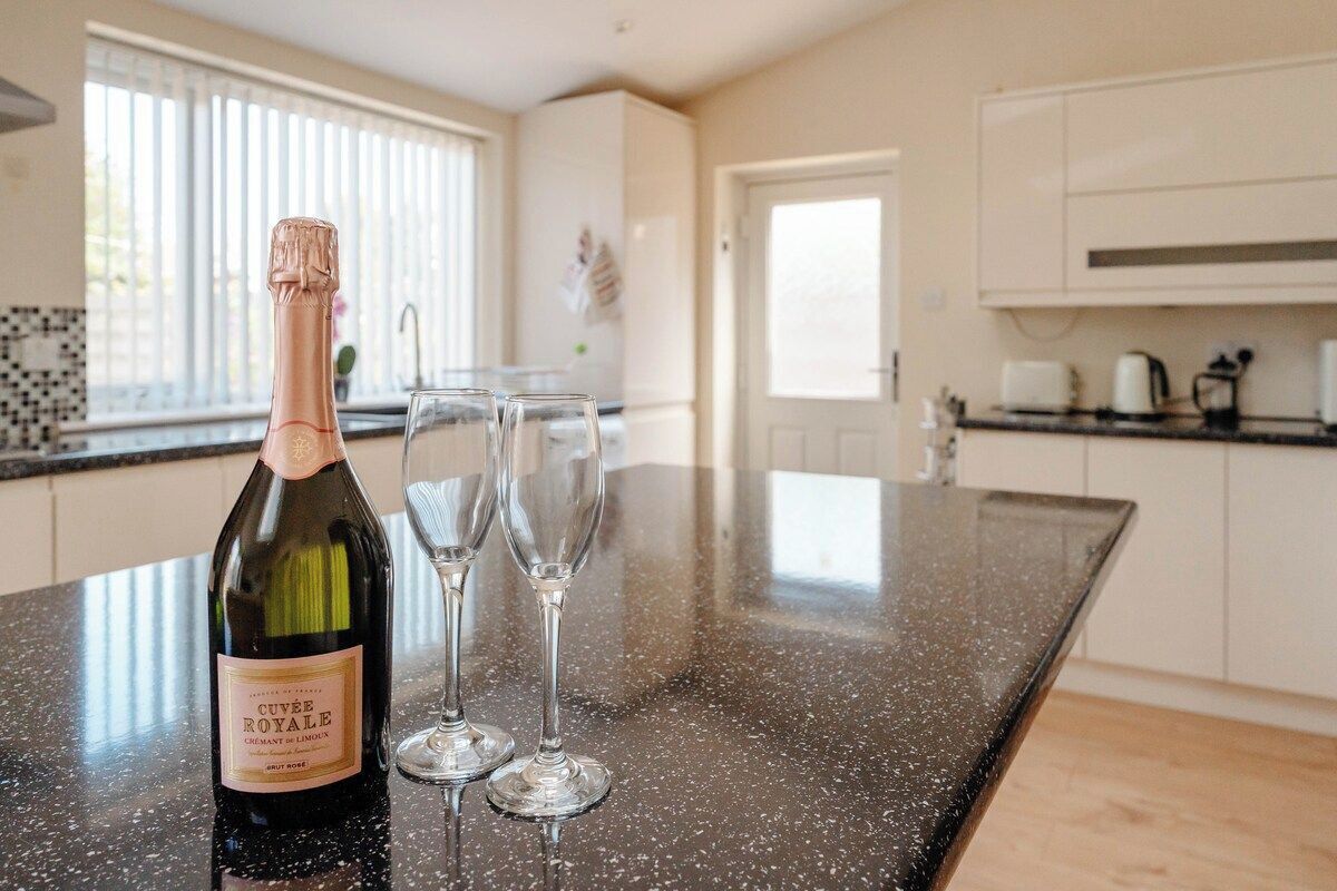 A kitchen counter with a bottle of wine and two glasses.
