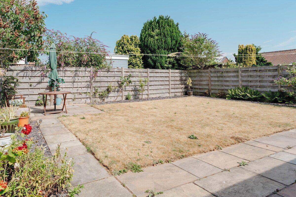 A backyard with a wooden fence, a table, and potted plants.