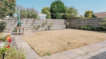 A backyard with a wooden fence, a table, and potted plants.