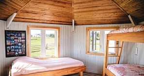 A room with a bunk bed, a single bed, and a poster on the wall.