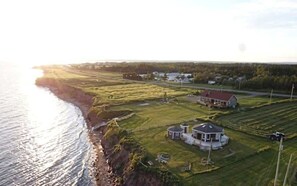 A coastal property with a large house, a smaller structure, and a well-maintained lawn.