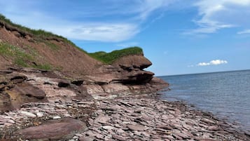 Eine felsige Küstenlinie mit einer grasbewachsenen Klippe und ruhigem Wasser.