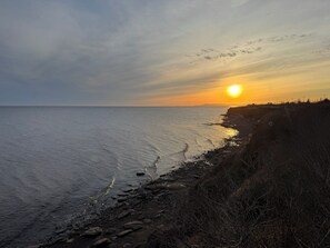 Rannikon auringonlasku, jossa on kivinen rantaviiva ja kirkas taivas.