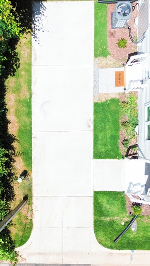 Una calle residencial con un camino de entrada despejado, un jardín y una casa con un porche y un buzón a la vista.